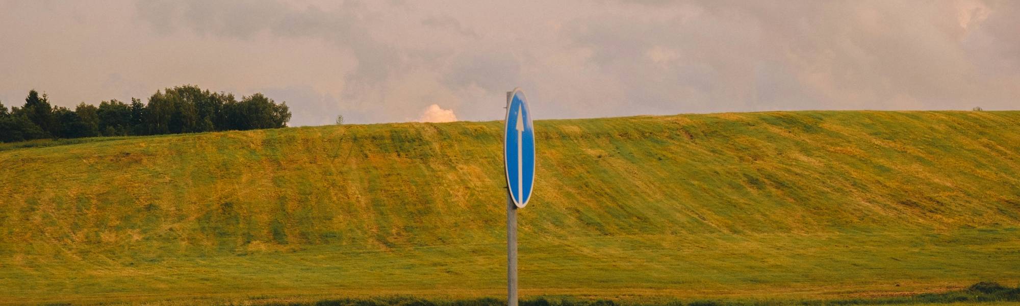 Stock photo showing a blue sedan on a scenic Manitoba road, representing auto insurance in the province